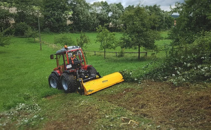 Traktor mit Mulcher arbeitet auf Wiese
